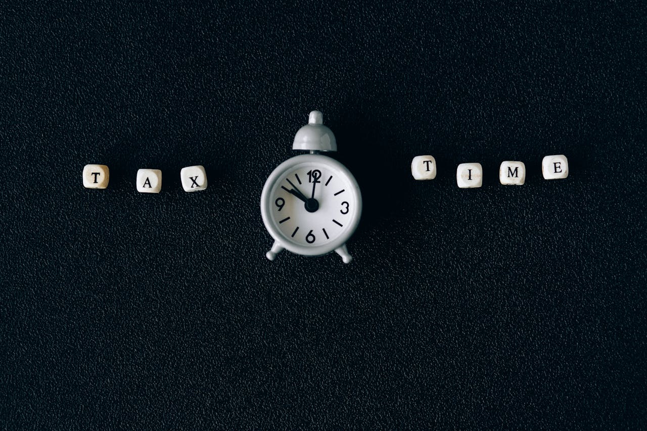 Conceptual image of tax time with clock and letter blocks on black background.